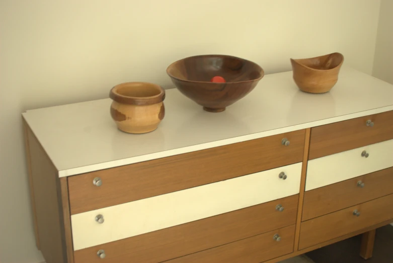 two wooden bowls are sitting on top of a dresser