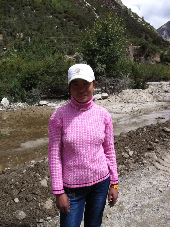 a person wearing a pink shirt and hat by the stream