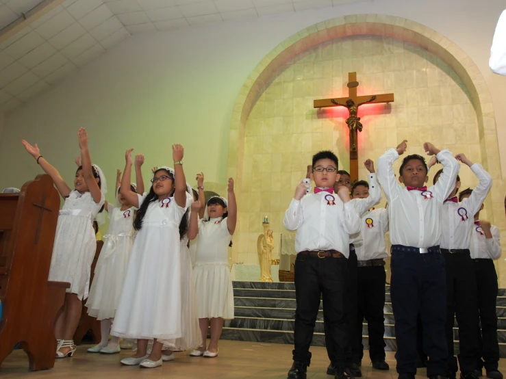 four children are raising their hands to say the word of jesus