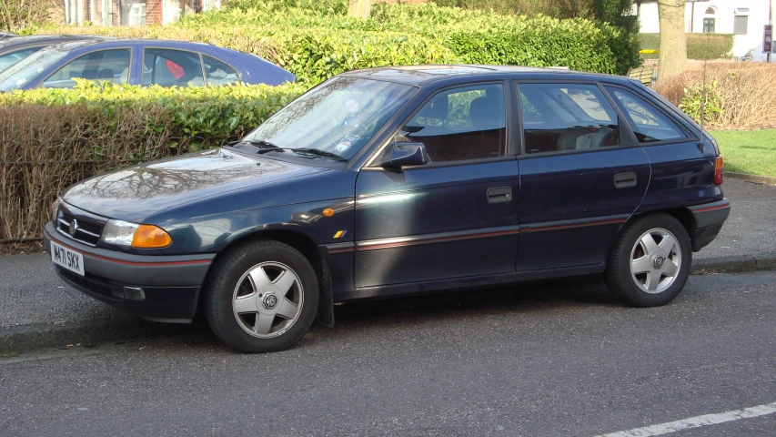 a blue car parked in front of a hedge