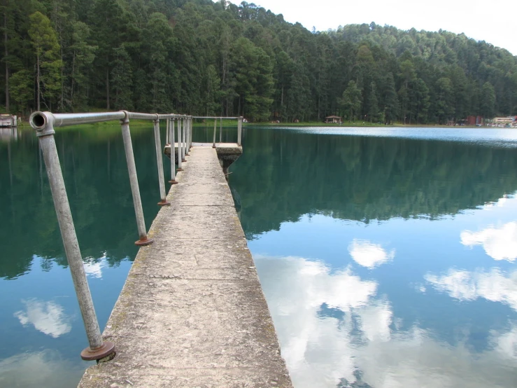 a long dock extending out to water with a mountain range in the background