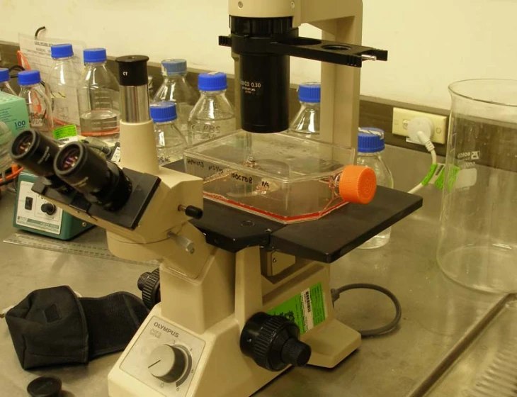 the microscope is on the table beside a glass bottle