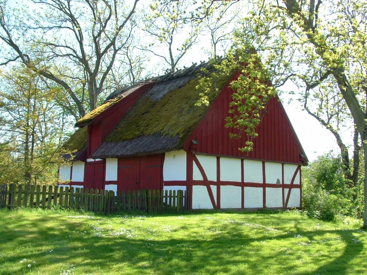 a red and white barn with a green roof and grass on it