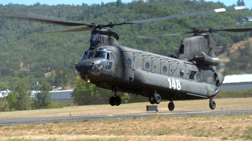 an army style helicopter is landing on a runway