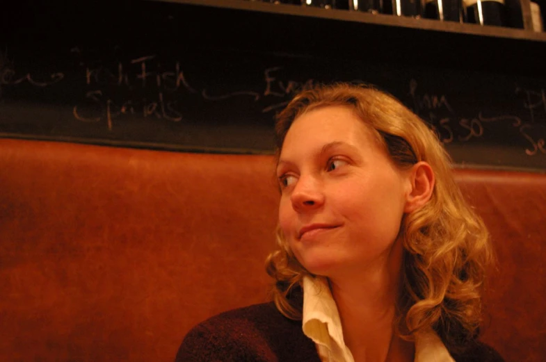 a young woman sitting on a train with writing on the wall behind her