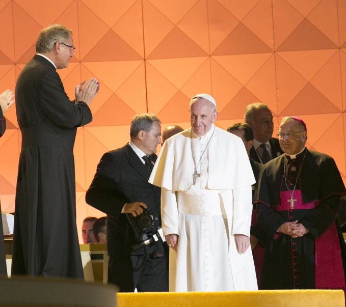 pope and other officials applaud a youngster in front of an audience