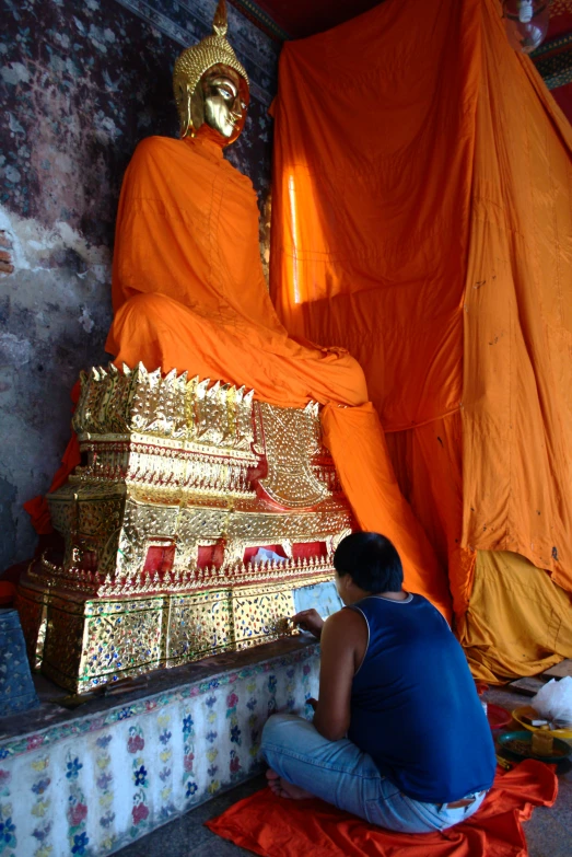 a monk in a blue shirt is doing a statue