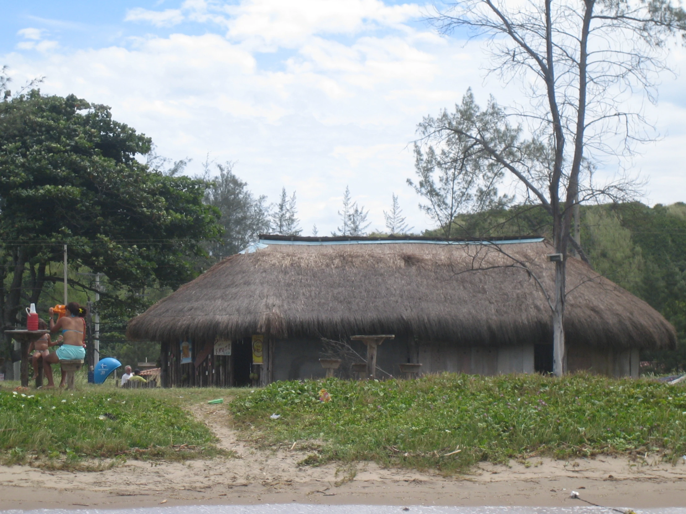 two people on horses by a hut with grass roof