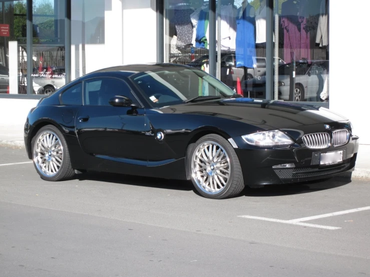 the black sports car parked on the sidewalk of a retail store