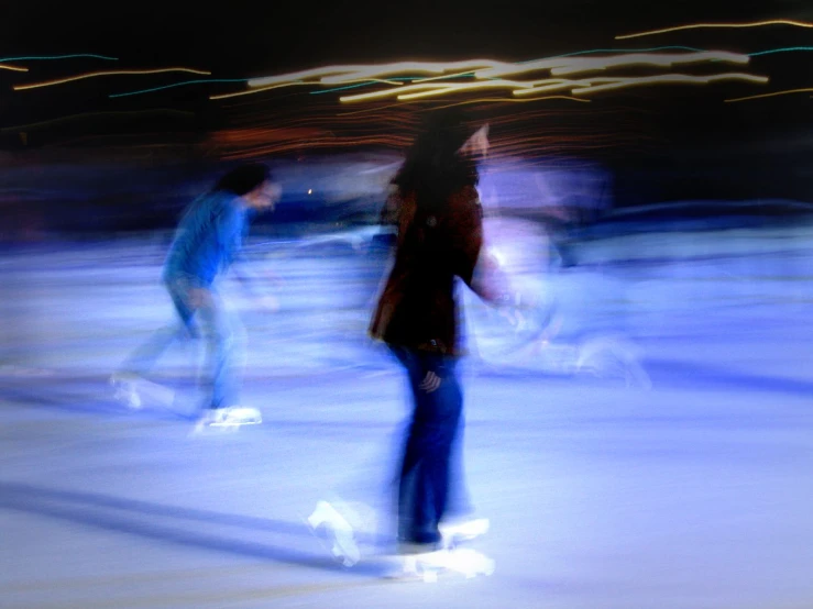 a blurry po of two skateboarders on an ice rink