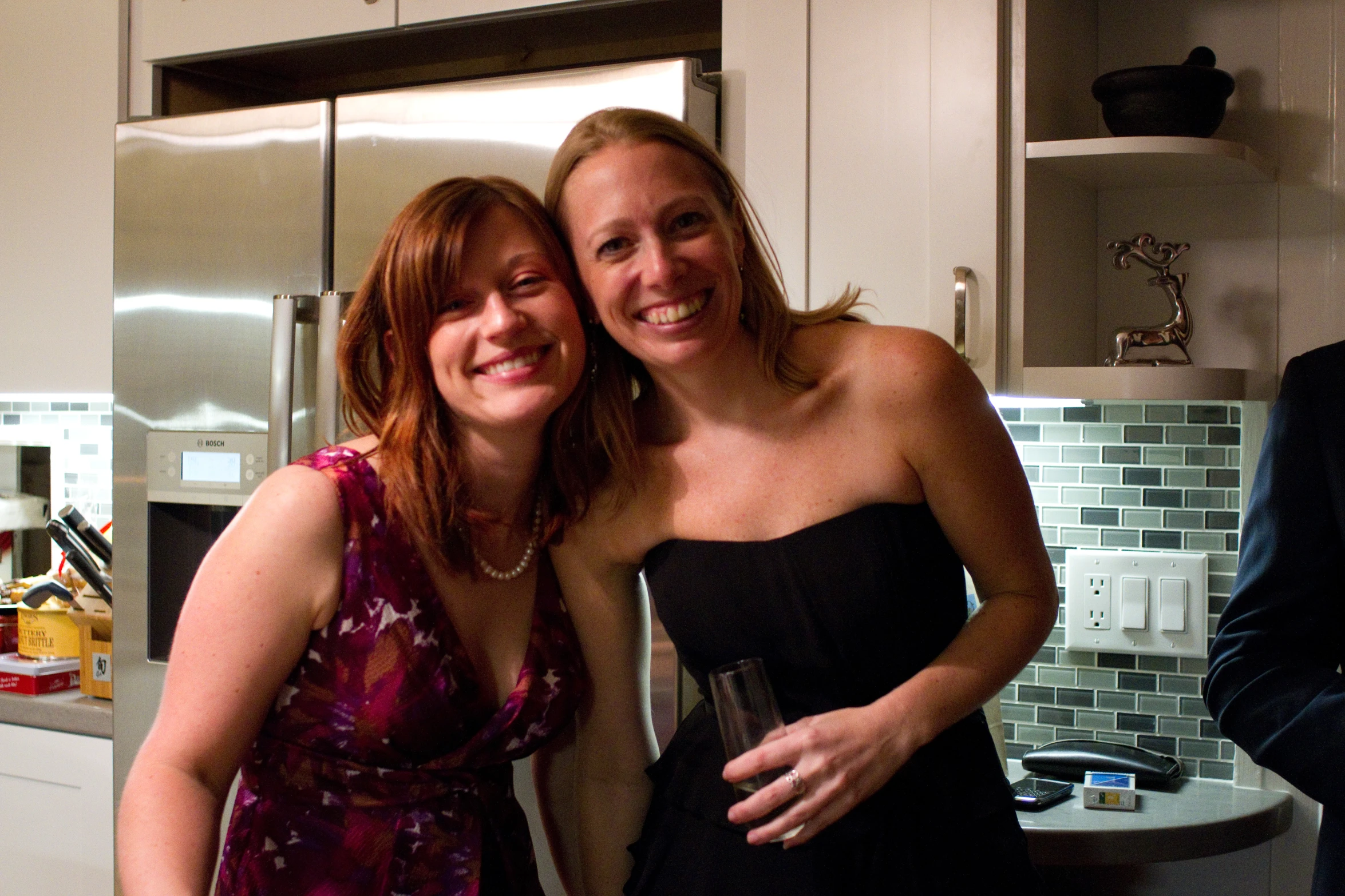 two ladies posing for the camera in a kitchen