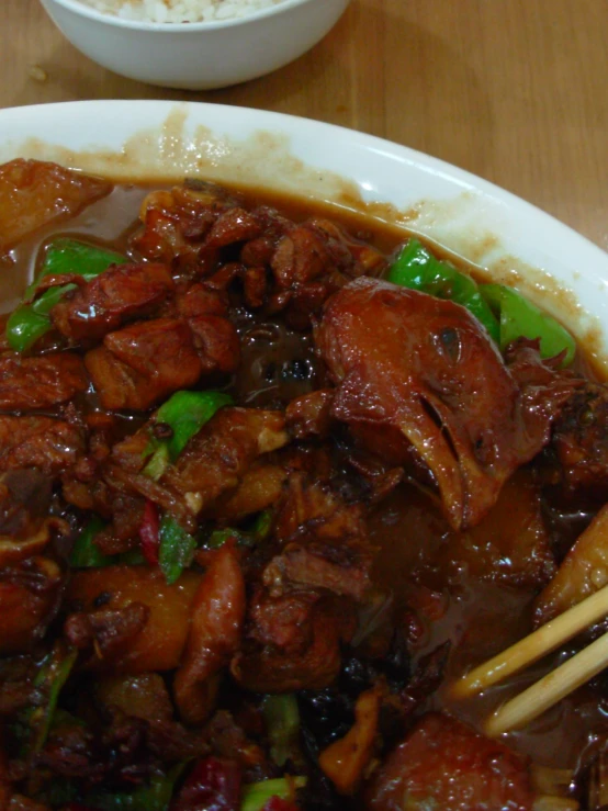 a bowl of meat and vegetables with chop sticks