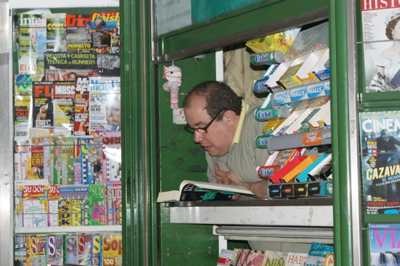 a man reading a book on top of a shelf