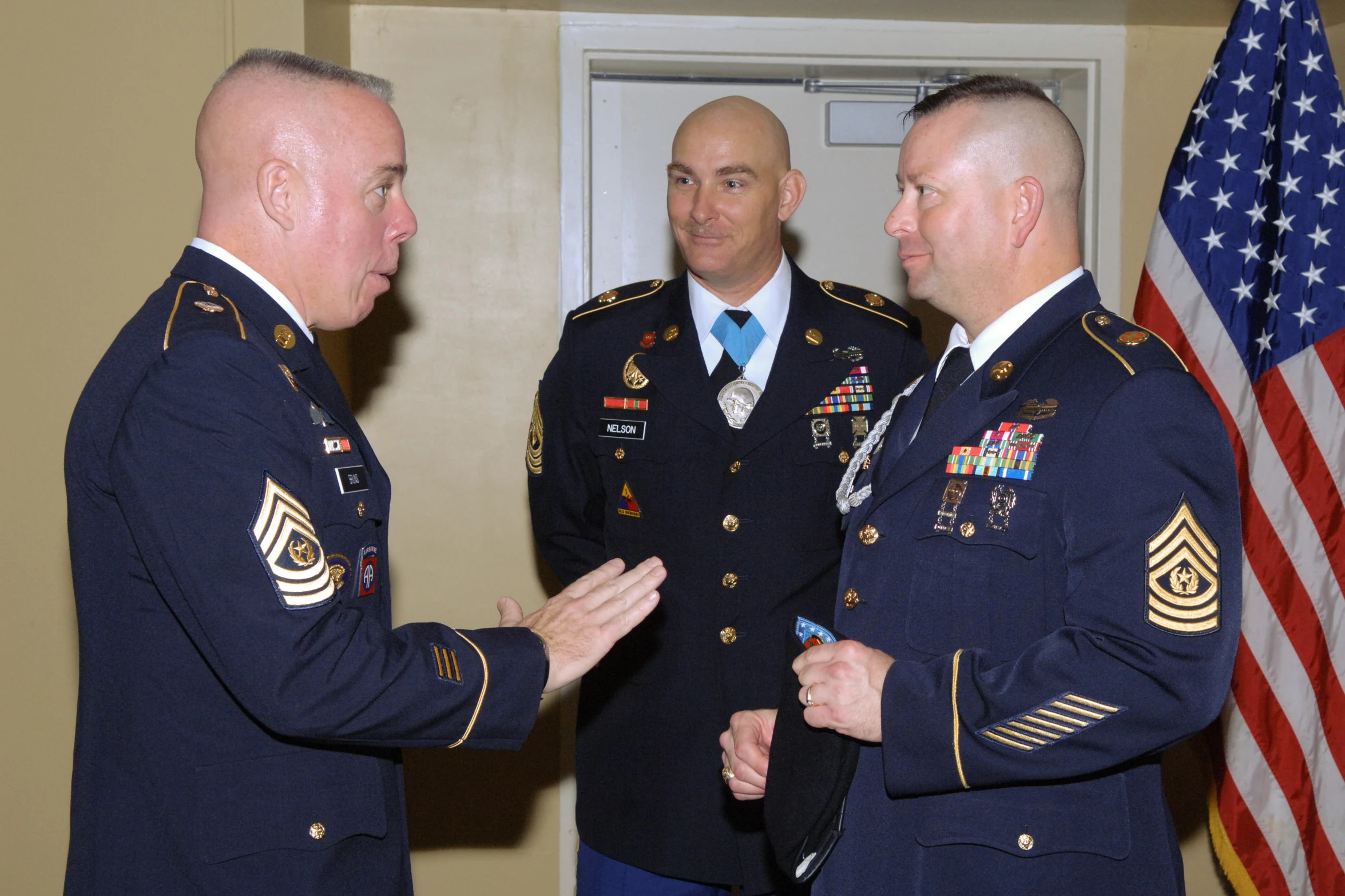 two men in military uniform greeting each other in front of a wall