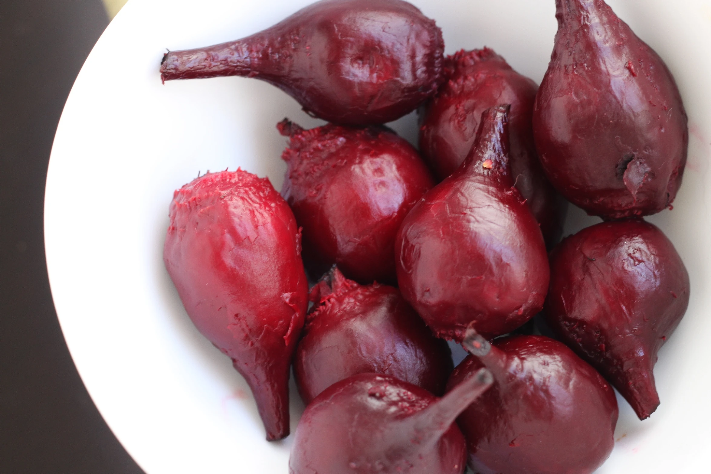 a white bowl full of peeled red fruits