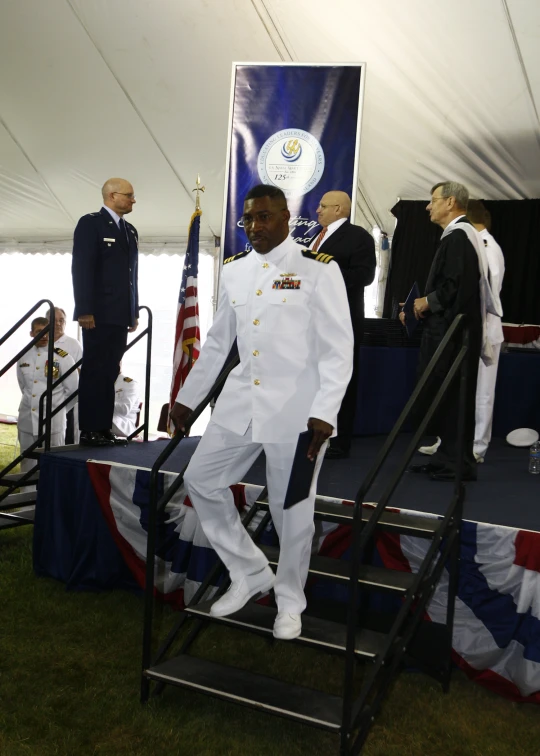 two people standing in front of flags next to a guard