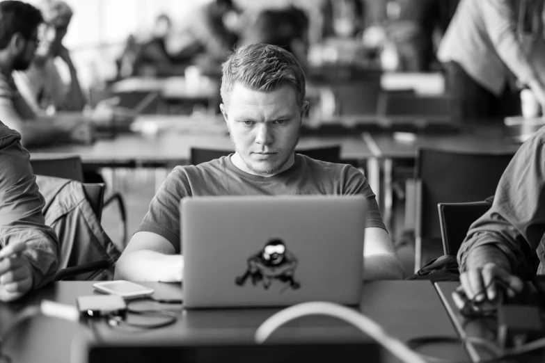 a man sitting at a table working on a laptop computer