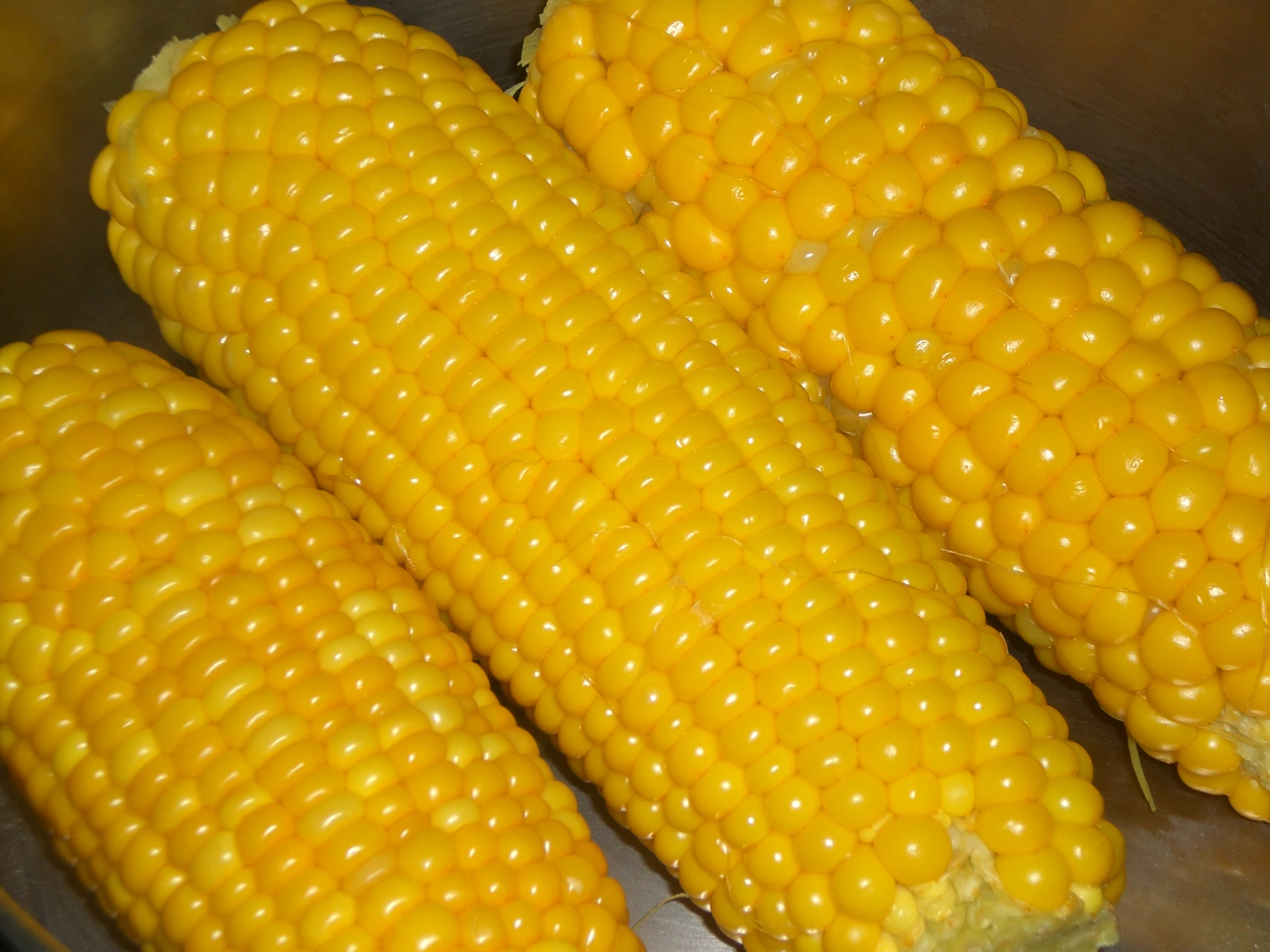 corn sitting on the cob in a stainless steel container