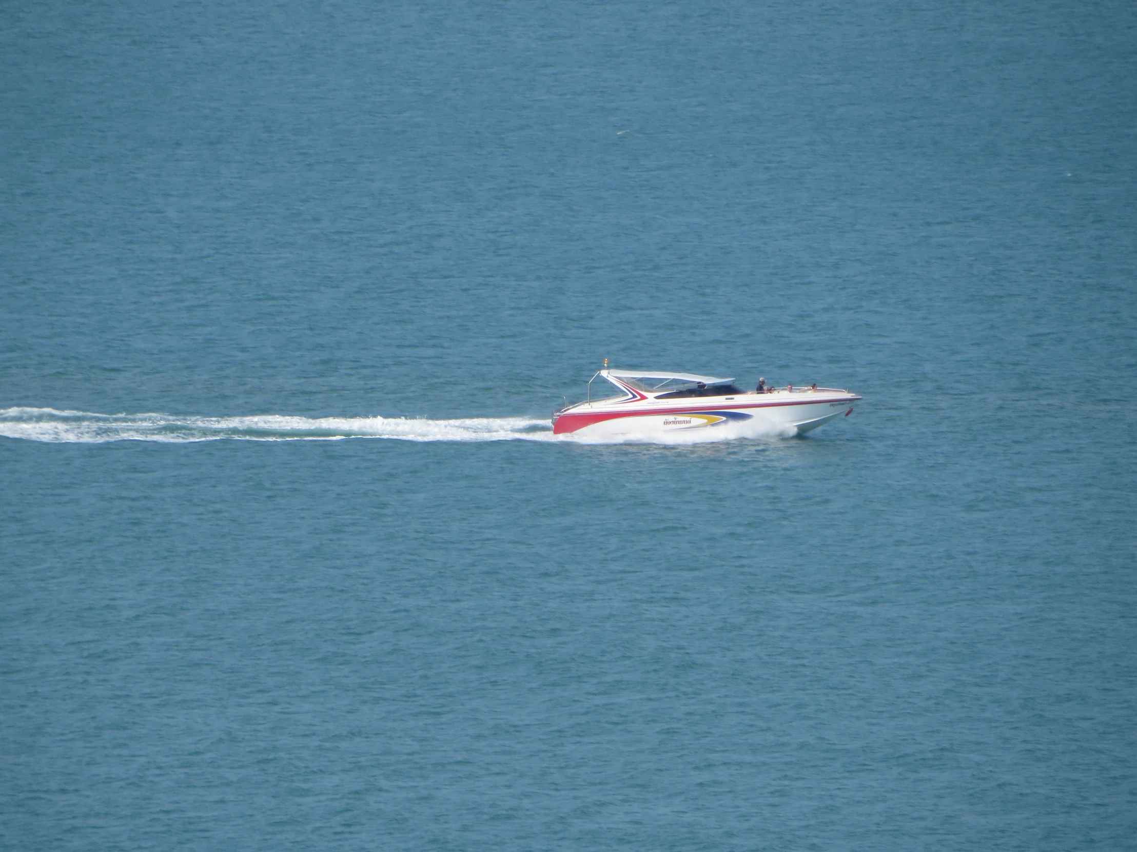 a white and red boat speeding across the ocean