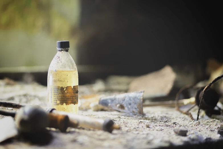 a bottle and some screws sitting on the ground