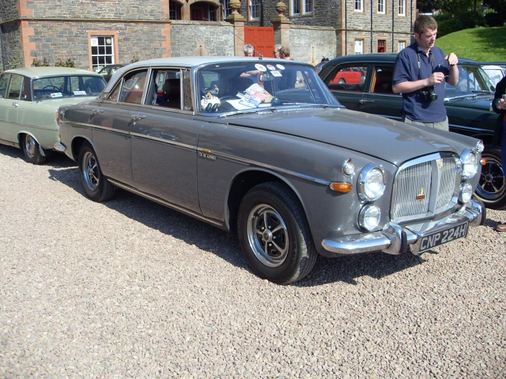 people are gathered to see antique cars on display