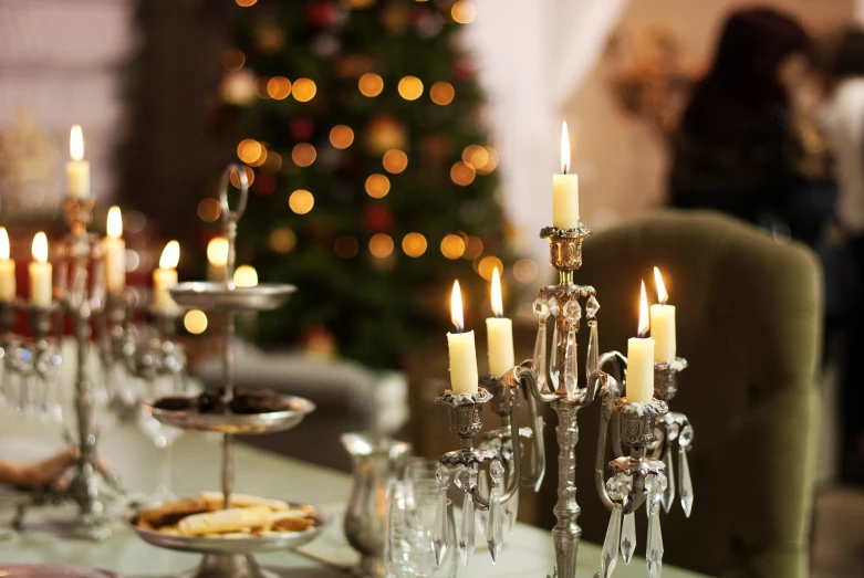 several silver candles stand on a table with plates of food