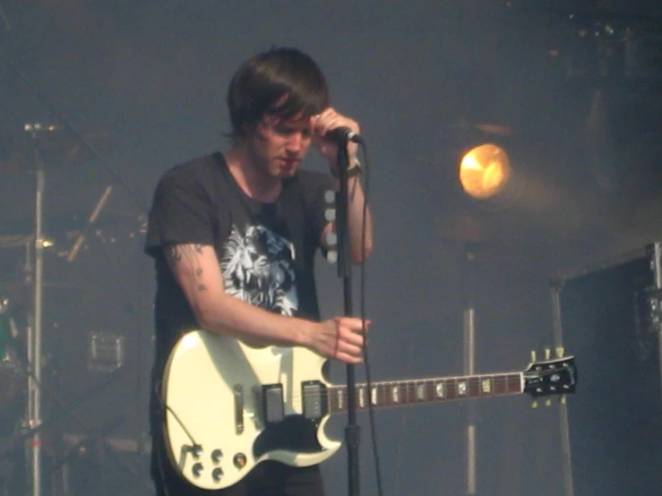 a man standing on stage holding a white guitar