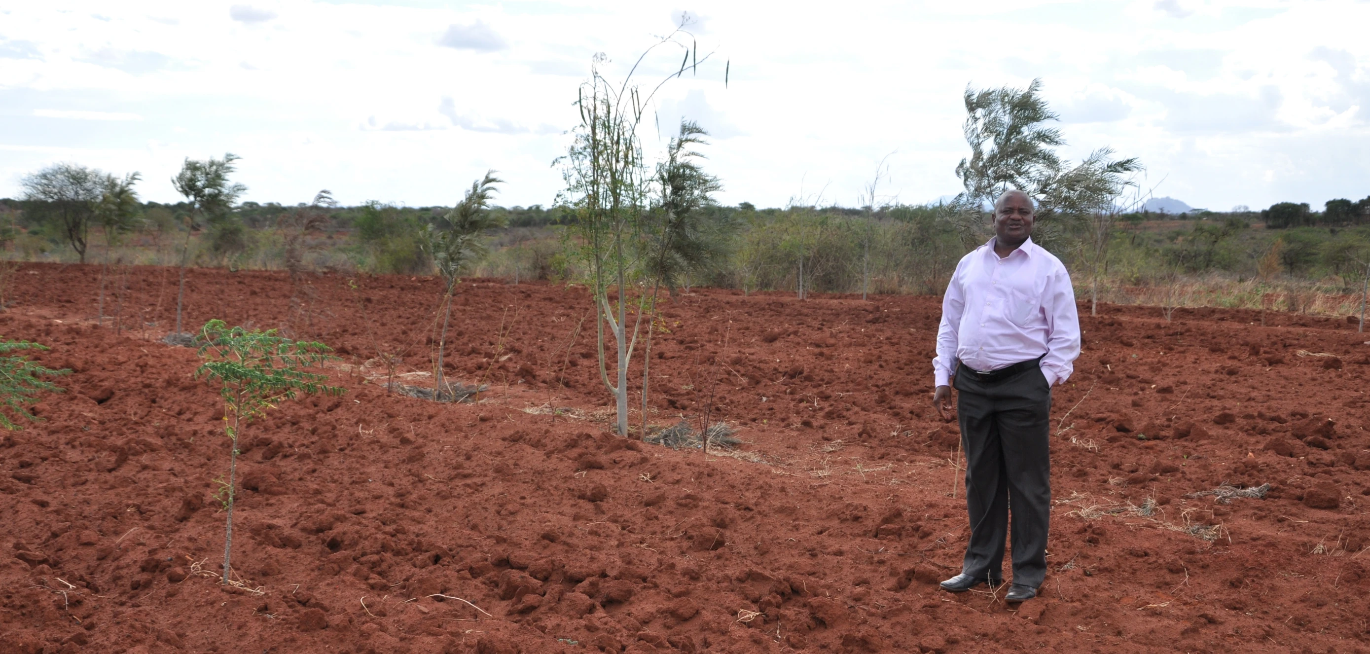 a man standing in the middle of a red earth field