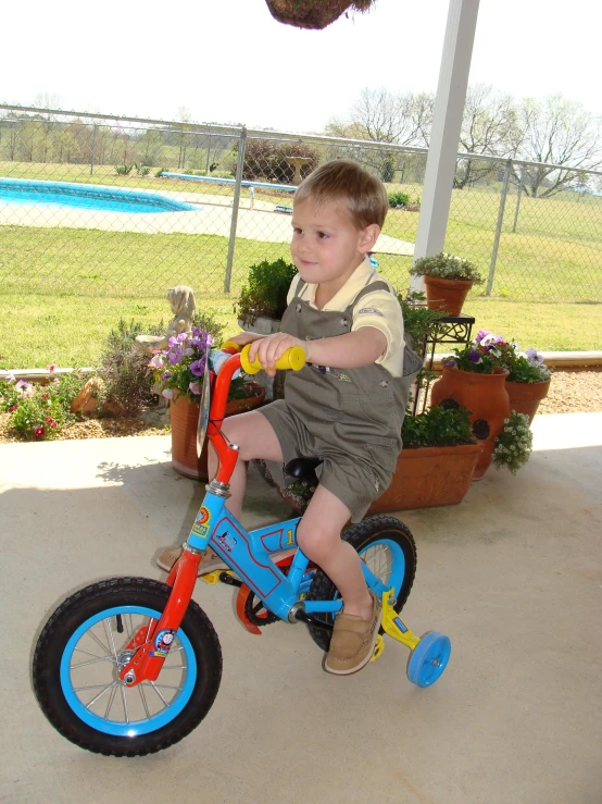 a boy is riding his blue bicycle in the yard