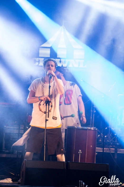 the boy sings on stage in front of a band