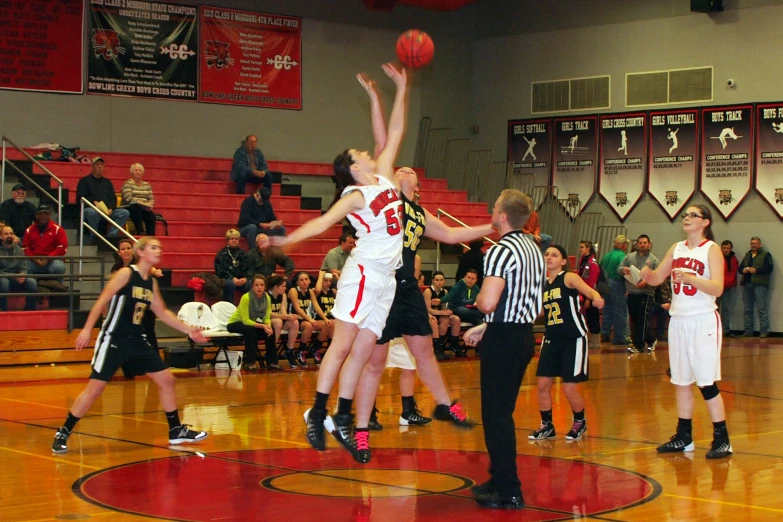 a group of young women playing basketball in a gym