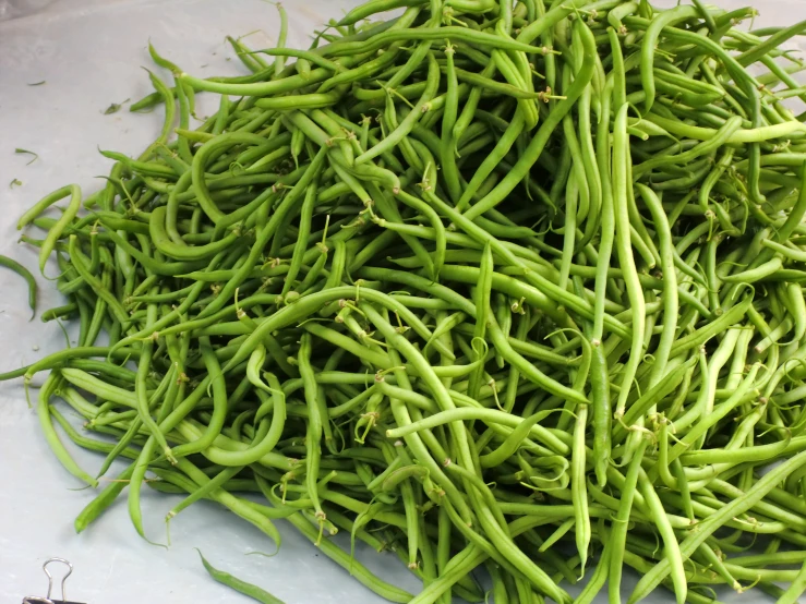 pile of green beans sitting on top of a white cloth