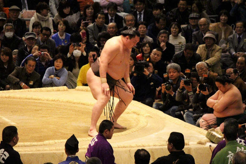 a sumo wrestler standing on one leg in front of a crowd