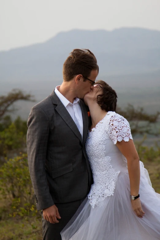 a bride and groom are standing in front of mountains