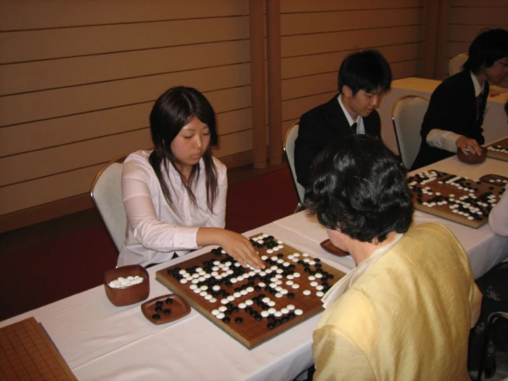 a man and woman with cupcakes and others sitting at table in front of a cake