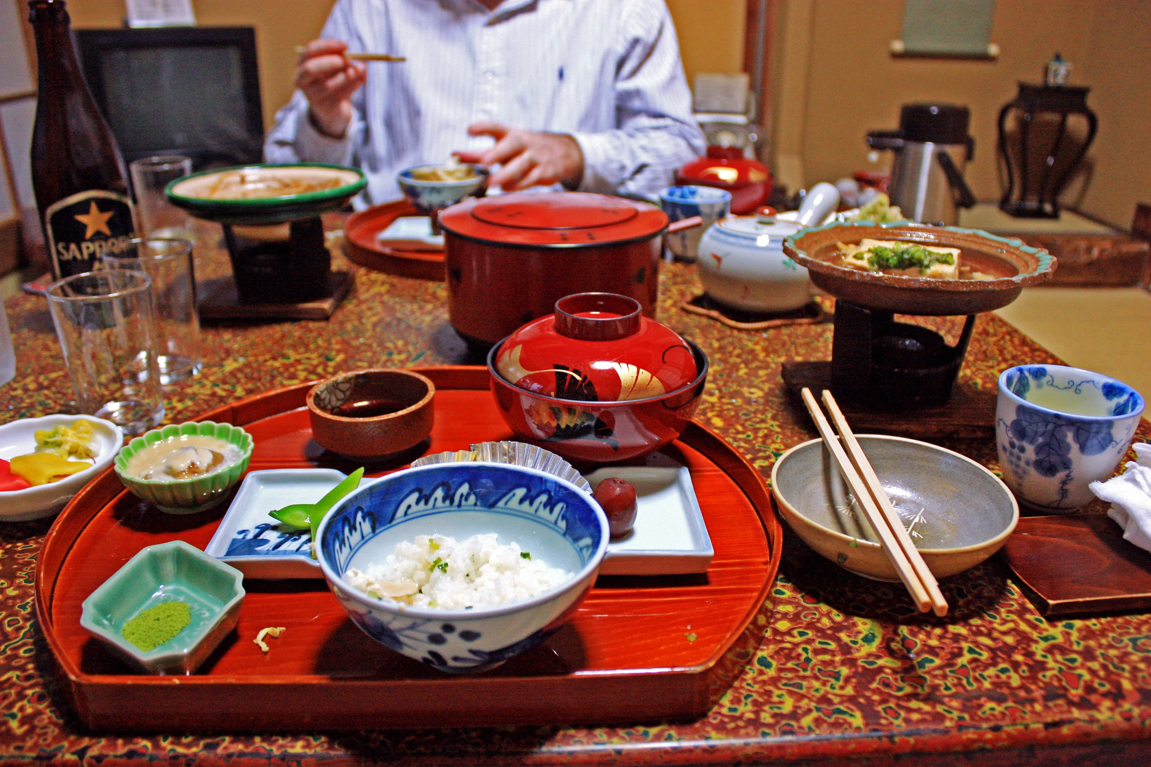 several bowls, plates and chopsticks on a table with a person