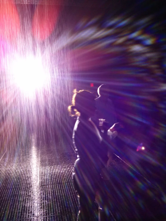 two people in the distance in a dark tunnel with bright light at the end of it