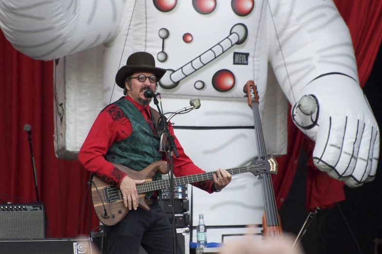 a person in a hat plays guitar near a statue