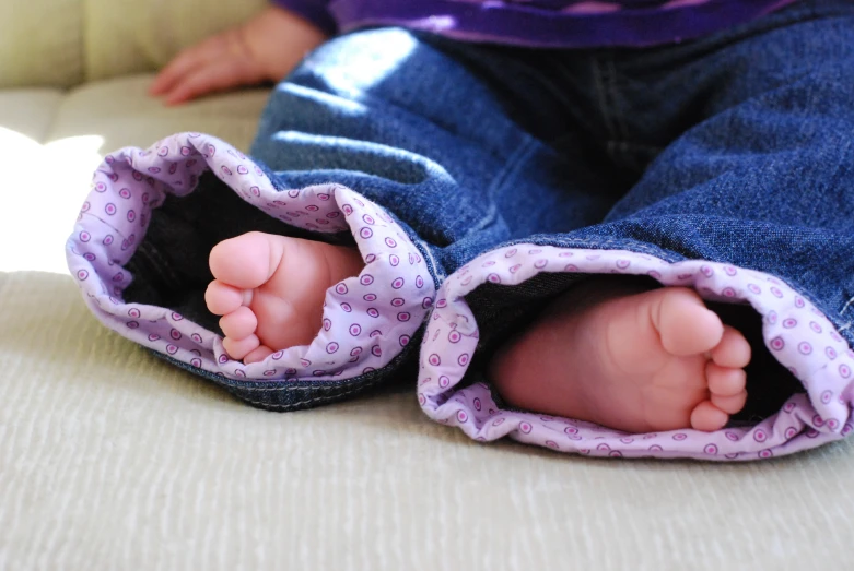 small child's feet and feet sticking out of a pair of jeans