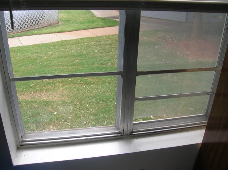 open window of a home with a grassy lawn behind it