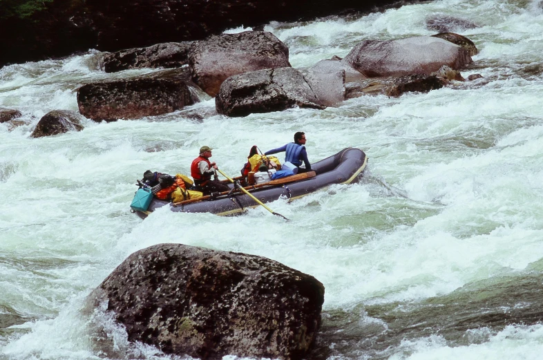 rafters on an inflatable boat make their way through a rapid river