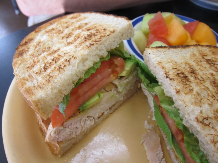 two sandwiches on a plate with fruit and strawberries