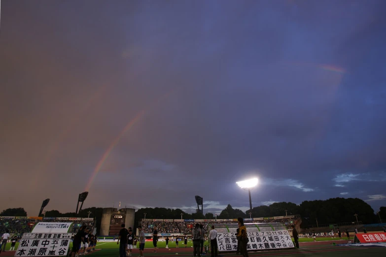 a rainbow appears above a stadium in the dark