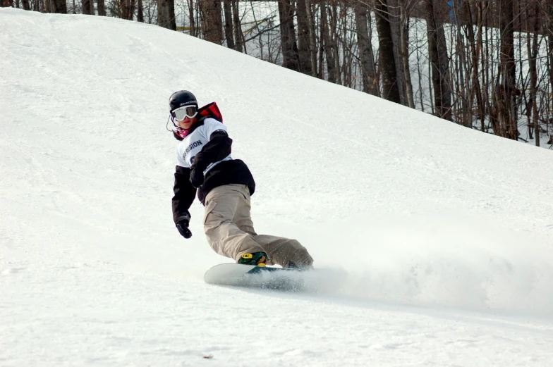 a snowboarder riding down a hill with white powder coming off the bottom