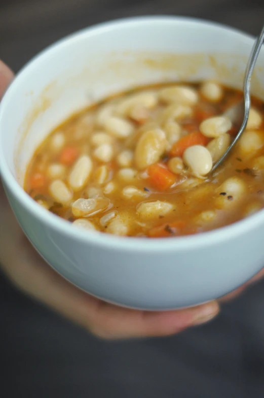 a person holding a bowl of soup with beans