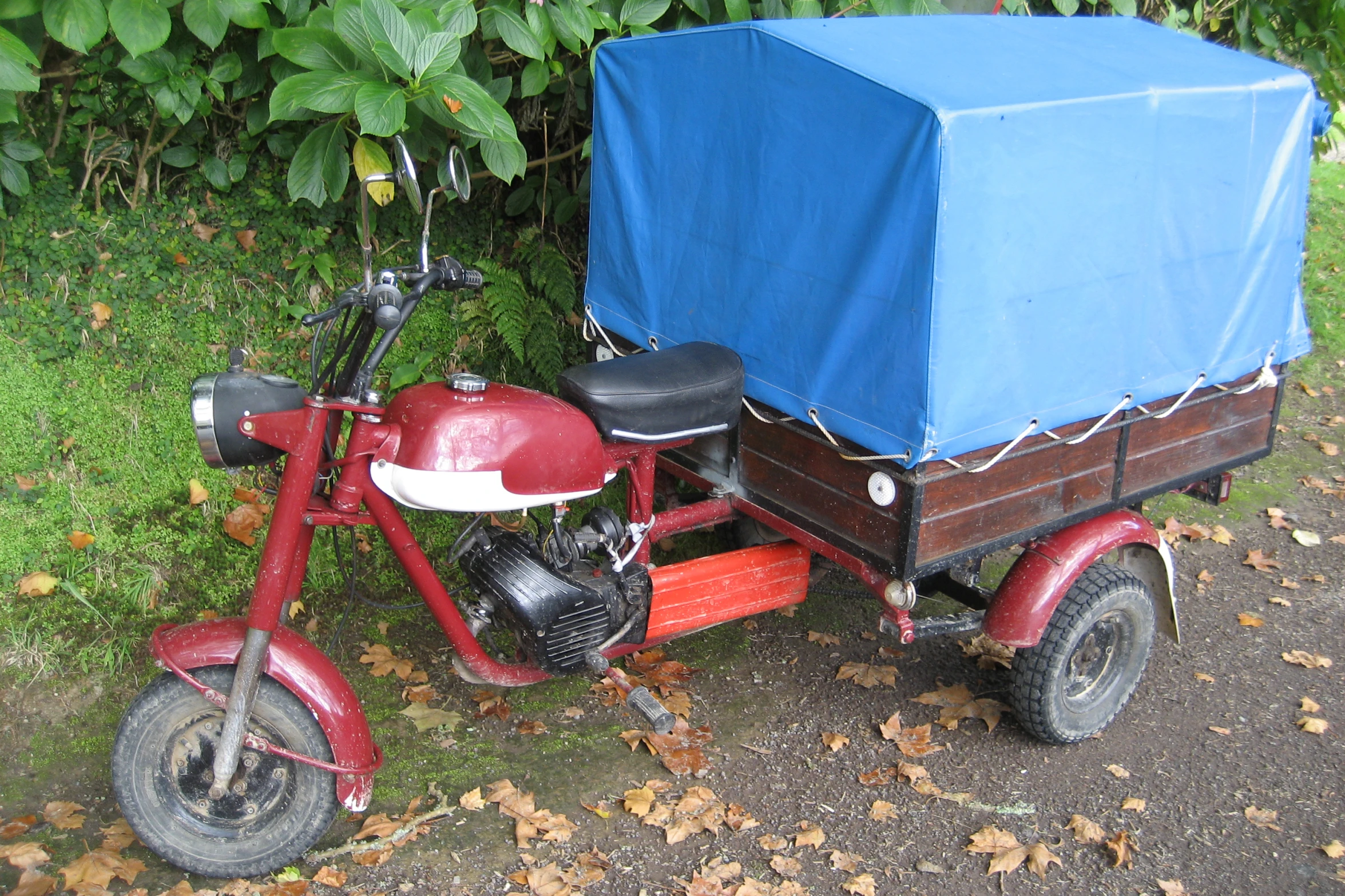 a motorcycle with two people on the side with a wagon strapped on it