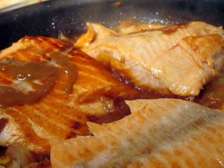 a plate with meat covered in sauce and onions