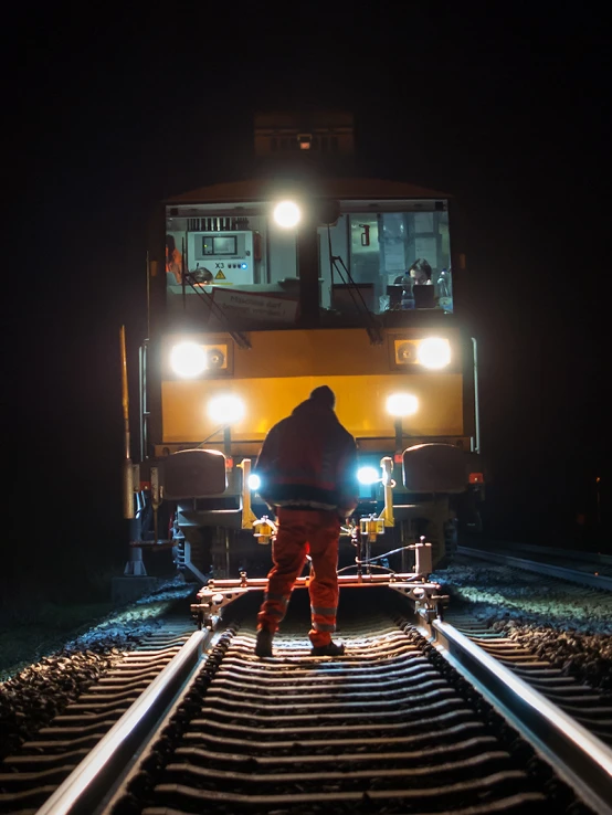 the man is walking down the tracks with headlamps