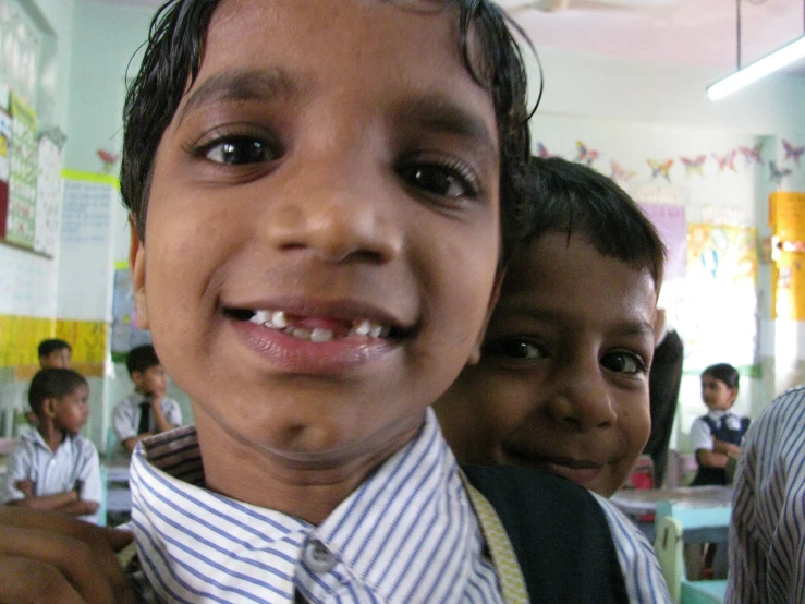 a little boy smiling at the camera while wearing suspenders and a neck tie