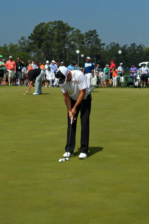 the golf player leans to get his putt on the green